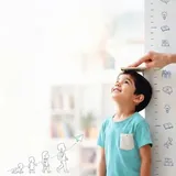 طفل يقيس طوله على مقياس النمو لدعم النمو المتوازن
